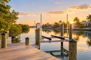 Private wooden dock with an empty boat lift on a calm Clearwater canal at golden hour.